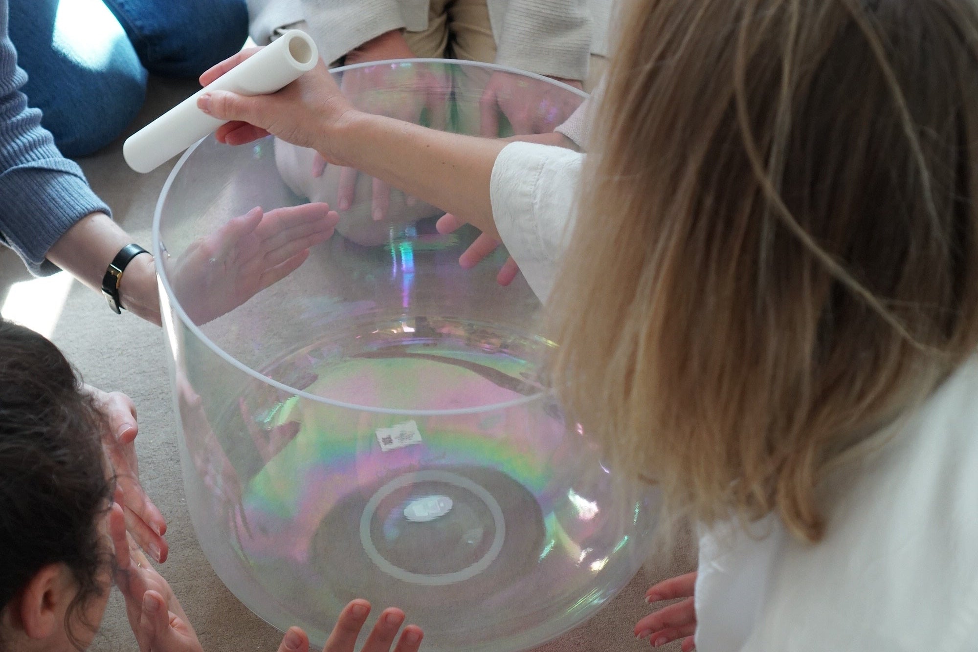 people feeling the vibrations of a big supergrade singing bowl